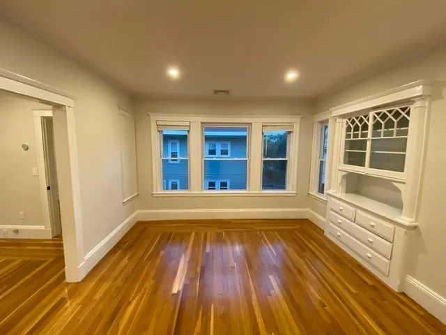 a view of an empty room with wooden floor and windows