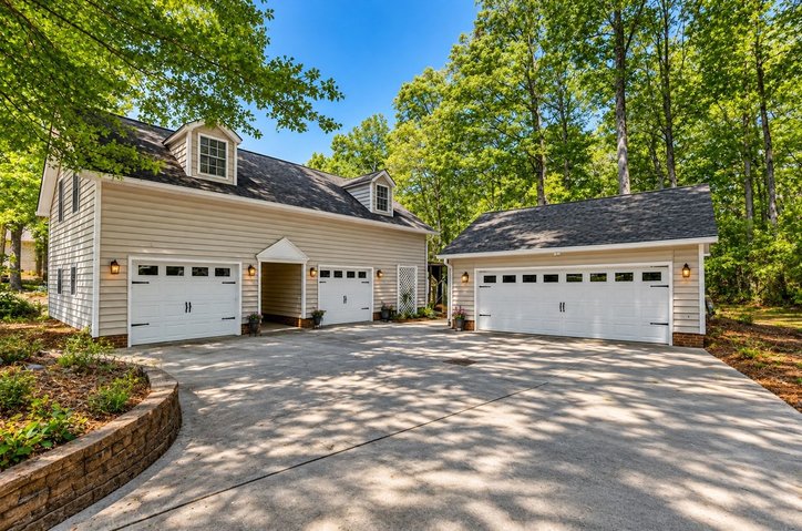 106 Pikes Ridge Anderson, SC 29626 - Photo 3 of 41 A spacious concrete driveway leads to multiple garage bays surrounded by mature trees.
