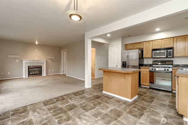 a kitchen with granite countertop a refrigerator and a stove top oven