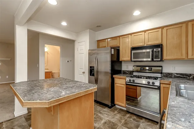 a kitchen with stainless steel appliances granite countertop a stove a refrigerator and a microwave