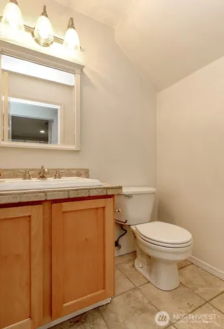 a bathroom with a granite countertop toilet sink and mirror