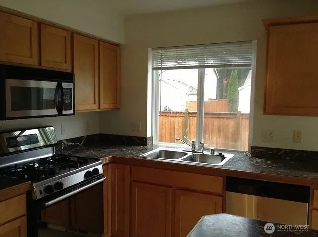 a kitchen with granite countertop a sink stainless steel appliances and cabinets