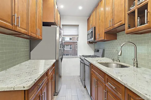 a kitchen with stainless steel appliances granite countertop a sink a stove and a wooden cabinets