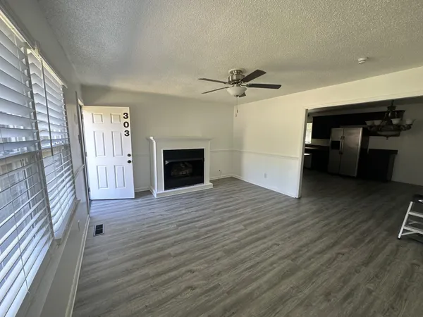a view of a livingroom with a fireplace a ceiling fan and wooden floor
