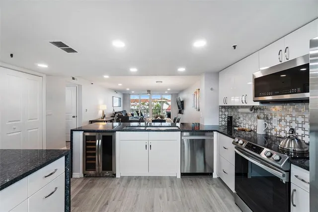 a kitchen with stainless steel appliances granite countertop a stove top oven a sink dishwasher and a microwave oven with wooden floor