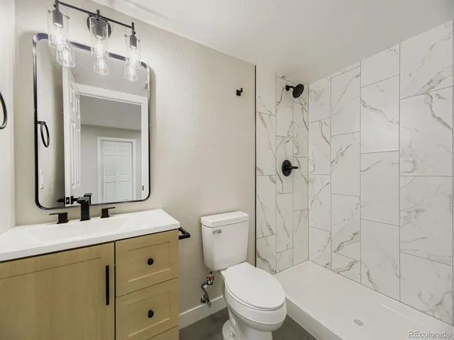 a bathroom with a toilet sink vanity and mirror