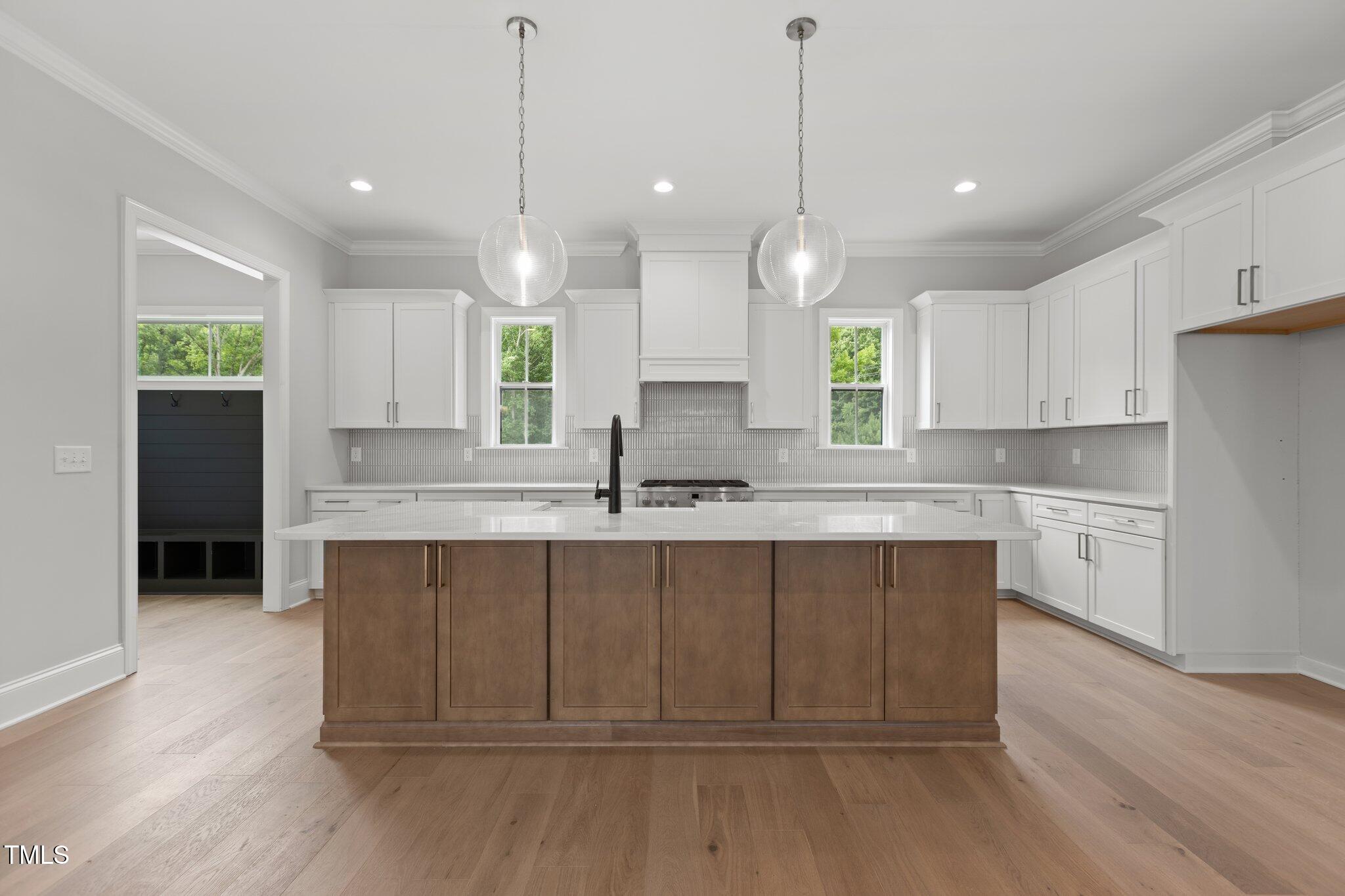 9305 Field Maple Court Raleigh, NC 27613 - Photo 5 of 13 a large kitchen with kitchen island white cabinets and wooden floor