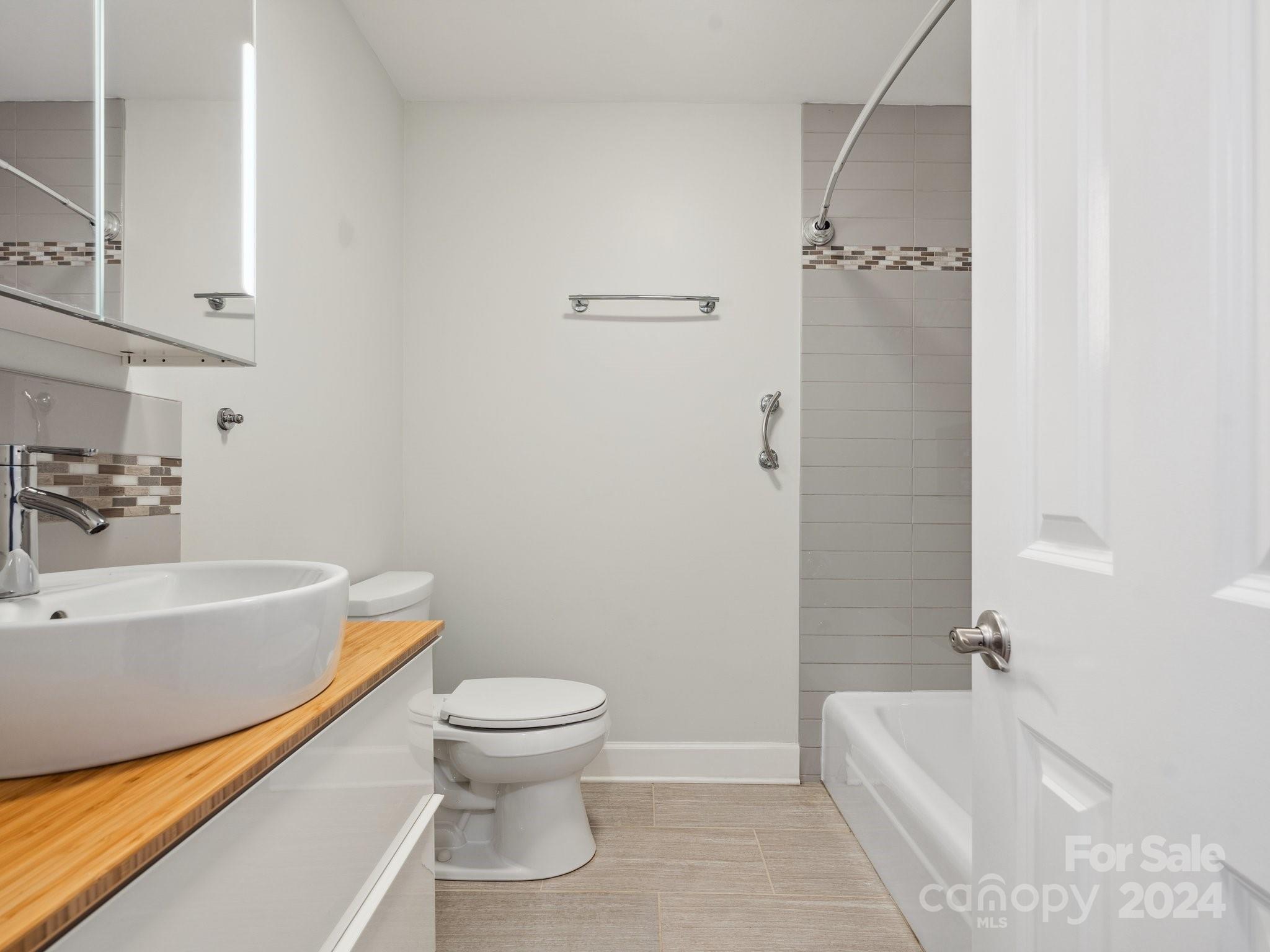 7631 Watercrest Road Charlotte, NC 28210 - Photo 20 of 42 a bathroom with a white bath tub a toilet and a sink