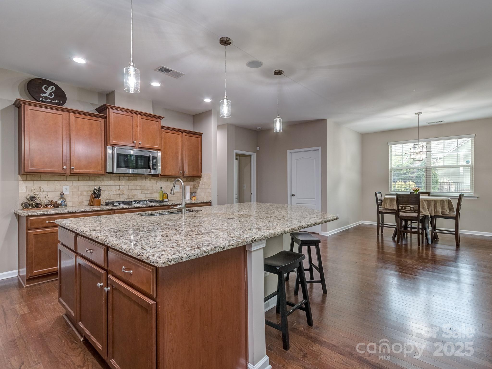 140 Halifax Drive Fort Mill, SC 29707 - Photo 13 of 38 a kitchen with stainless steel appliances granite countertop a stove top oven a sink a dining table and chairs with wooden floor
