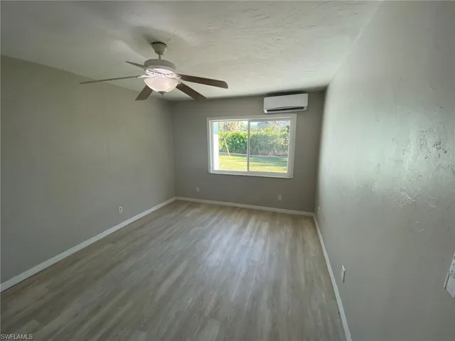 an empty room with wooden floor chandelier fan and windows