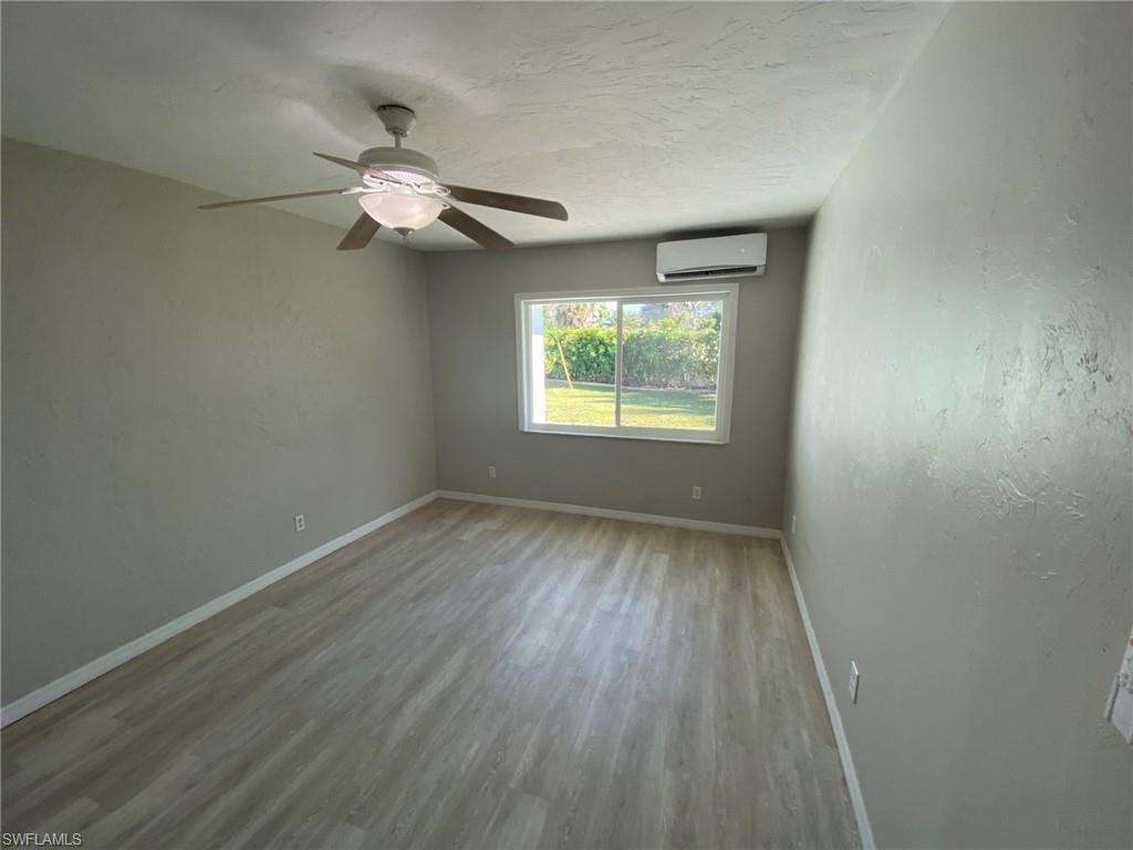 22 Constitution Drive Naples, FL 34112 - Photo 28 of 30 an empty room with wooden floor chandelier fan and windows