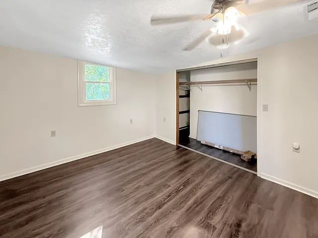 an empty room with wooden floor closet and windows