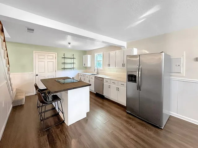 a kitchen with stainless steel appliances a dining table chairs refrigerator and sink