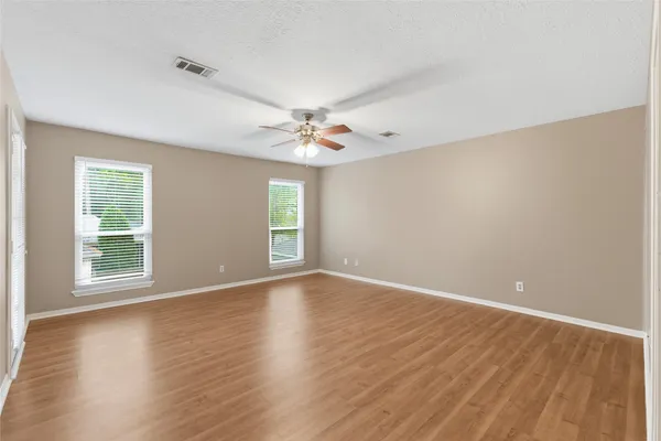 a view of an empty room with window and wooden floor