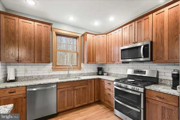 a kitchen with stainless steel appliances granite countertop a stove a sink and a microwave