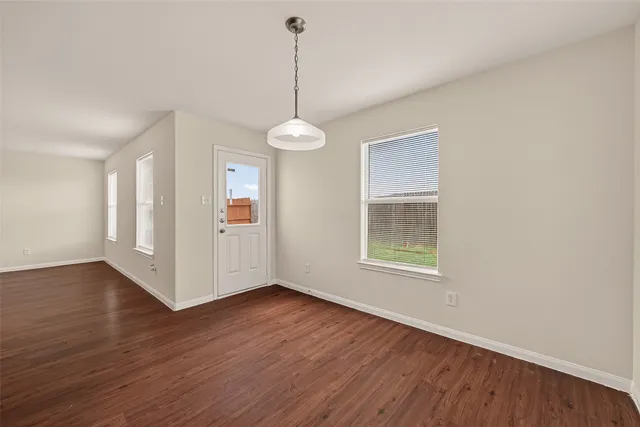 a view of an empty room with window and wooden floor