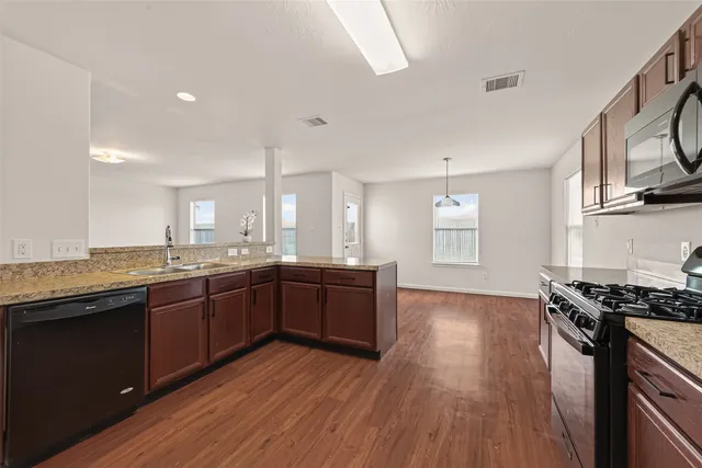 a large kitchen with stainless steel appliances granite countertop a stove and a wooden floors