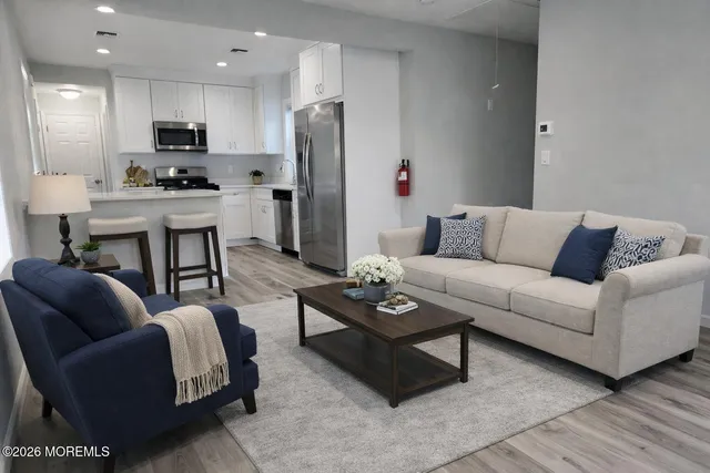 a living room with furniture a refrigerator and a flat screen tv