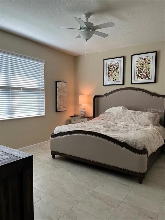 9879 Southwest 99th Loop Ocala, FL 34481 - Photo 9 of 12 a bedroom with a bed and a lamp on table