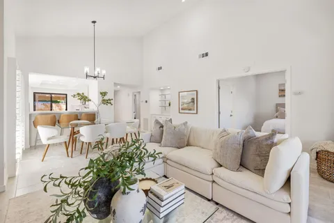 a living room with furniture kitchen view and a chandelier