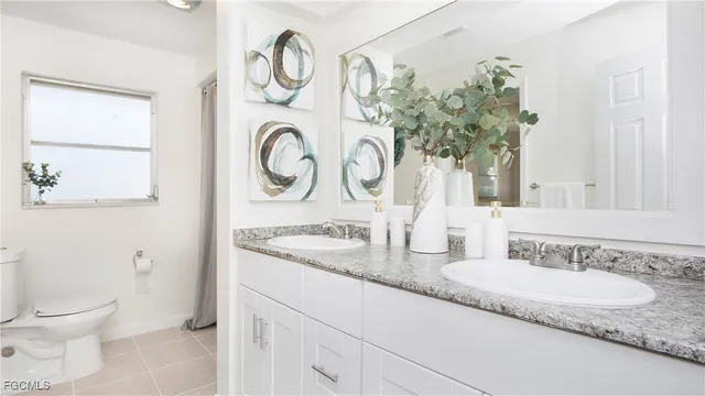 a bathroom with a granite countertop sink and a toilet