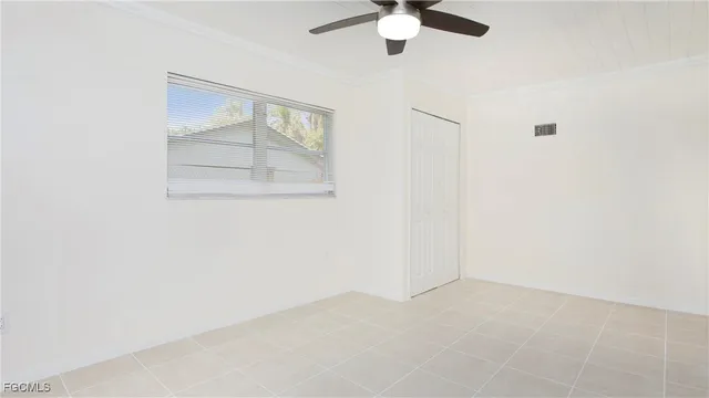 an empty room with a chandelier fan and windows