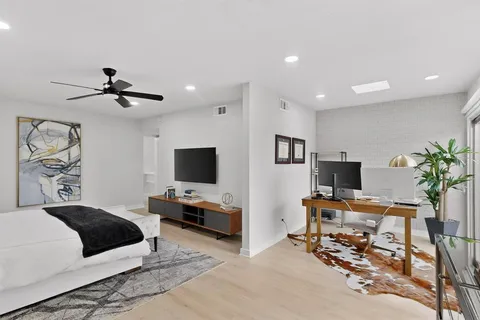 a bedroom with a bed a window and a flat screen tv
