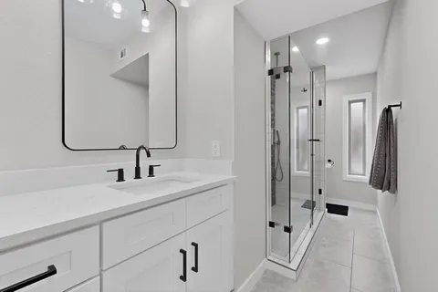 a bathroom with a double vanity sink mirror and shower