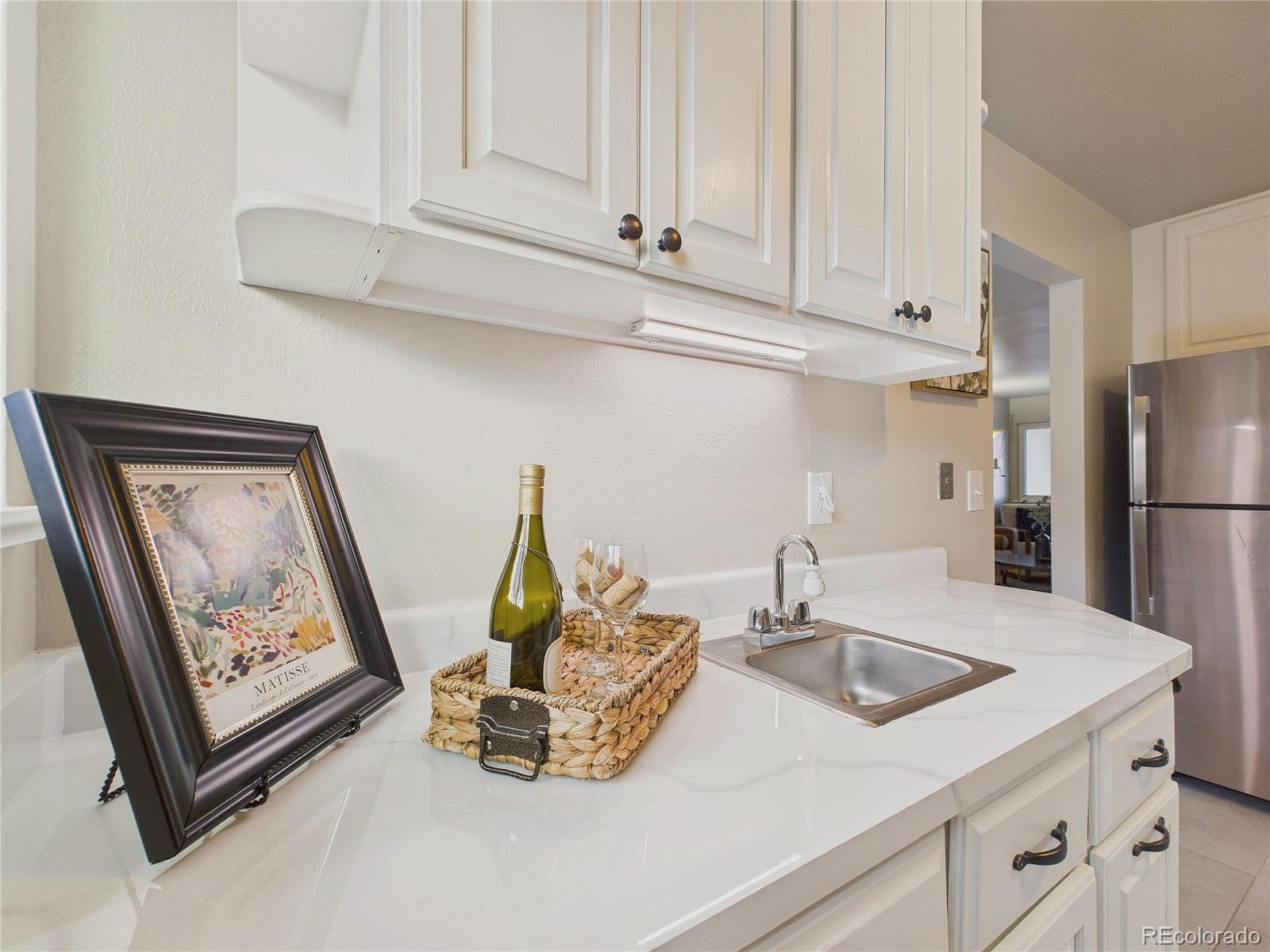 6085 Simms Street Arvada, CO 80004 - Photo 23 of 32 a kitchen with stainless steel appliances granite countertop a sink a refrigerator and a white cabinets