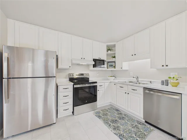 a kitchen with stainless steel appliances granite countertop a refrigerator sink stove and white cabinets