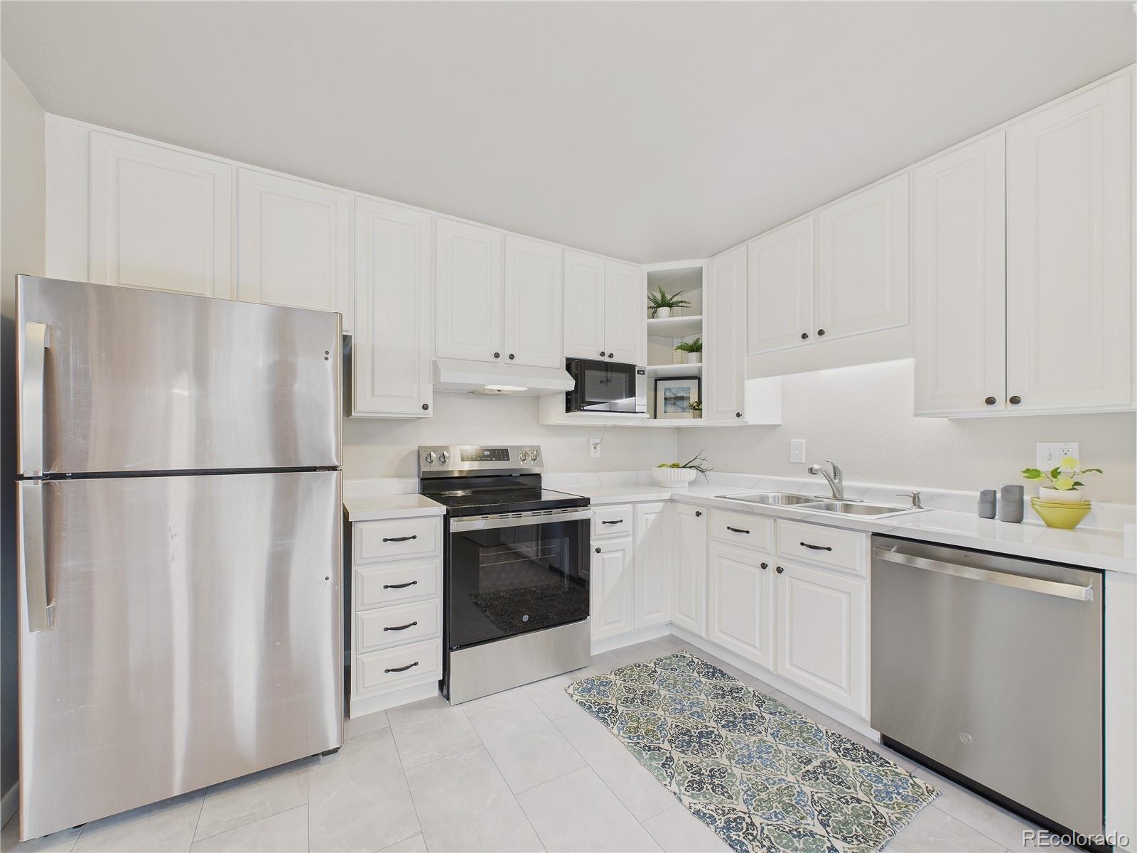 6085 Simms Street Arvada, CO 80004 - Photo 3 of 32 a kitchen with stainless steel appliances granite countertop a refrigerator sink stove and white cabinets