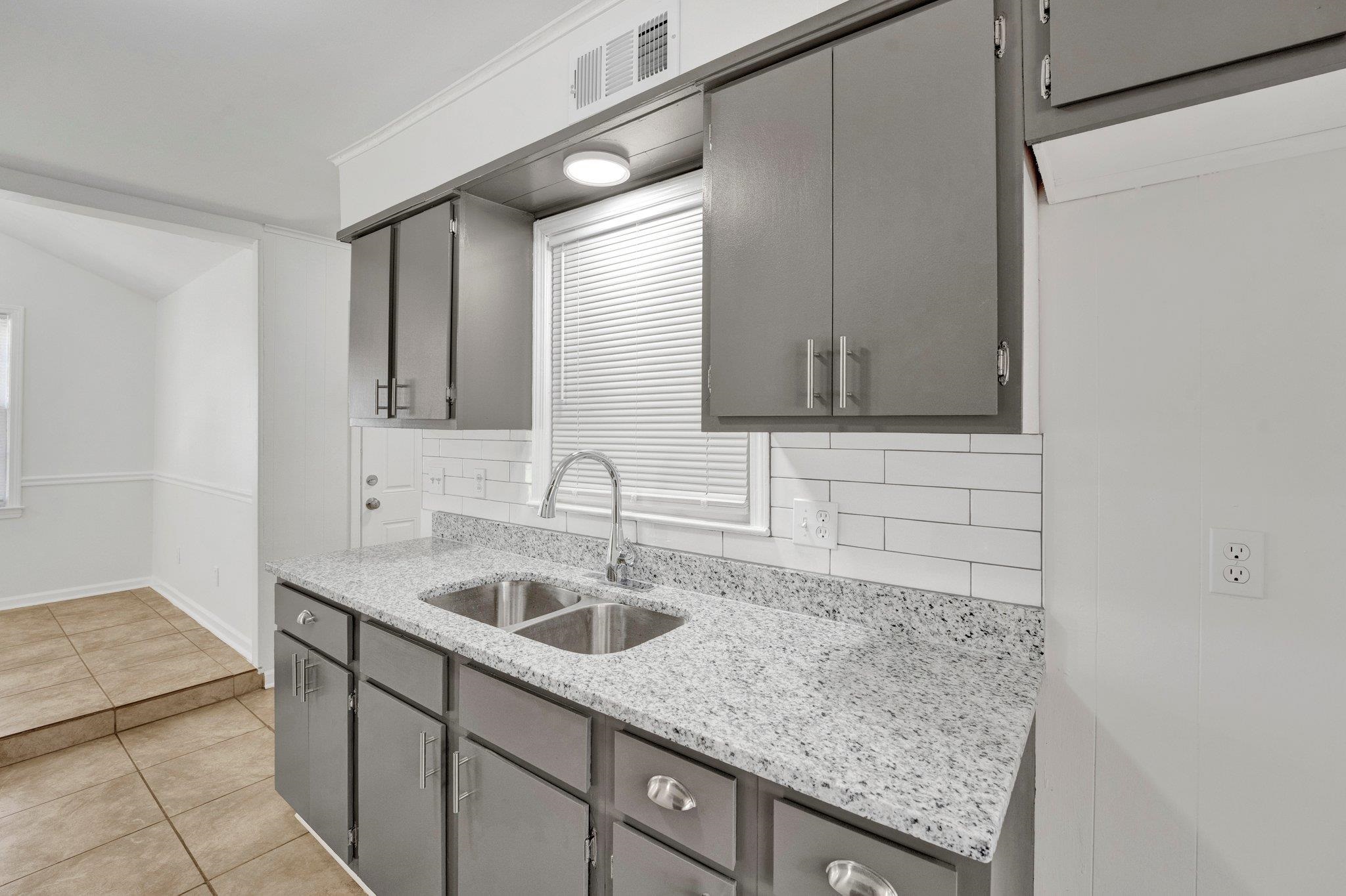 4382 Ruth Drive Memphis, TN 38109 - Photo 11 of 32 Kitchen featuring gray cabinetry, decorative backsplash, and sink