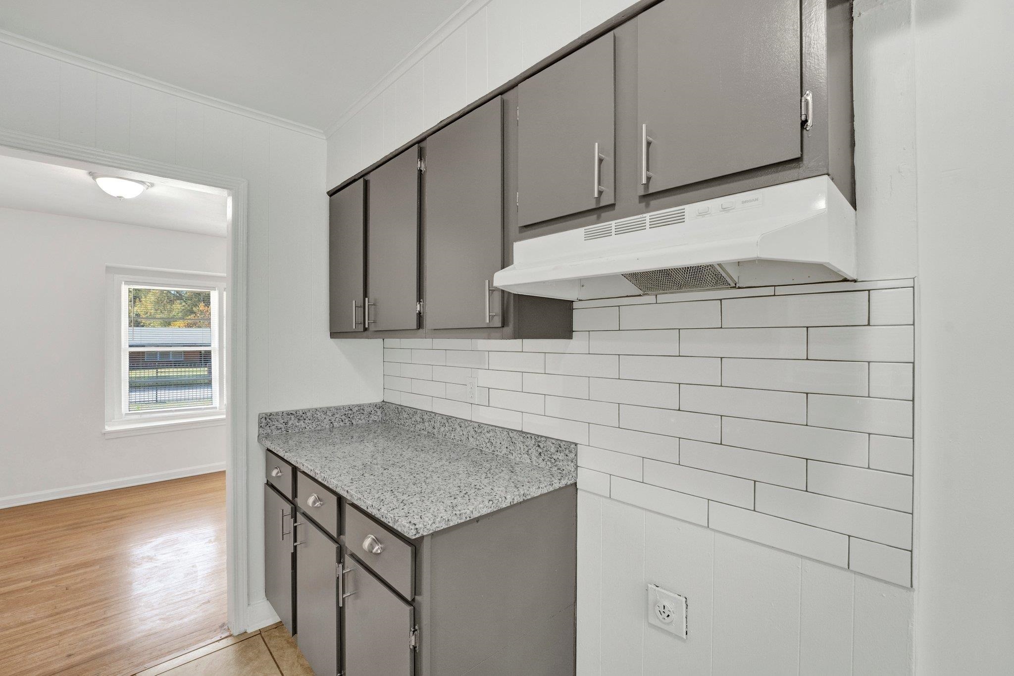 4382 Ruth Drive Memphis, TN 38109 - Photo 12 of 32 Kitchen featuring gray cabinets, light hardwood / wood-style flooring, ornamental molding, and tasteful backsplash