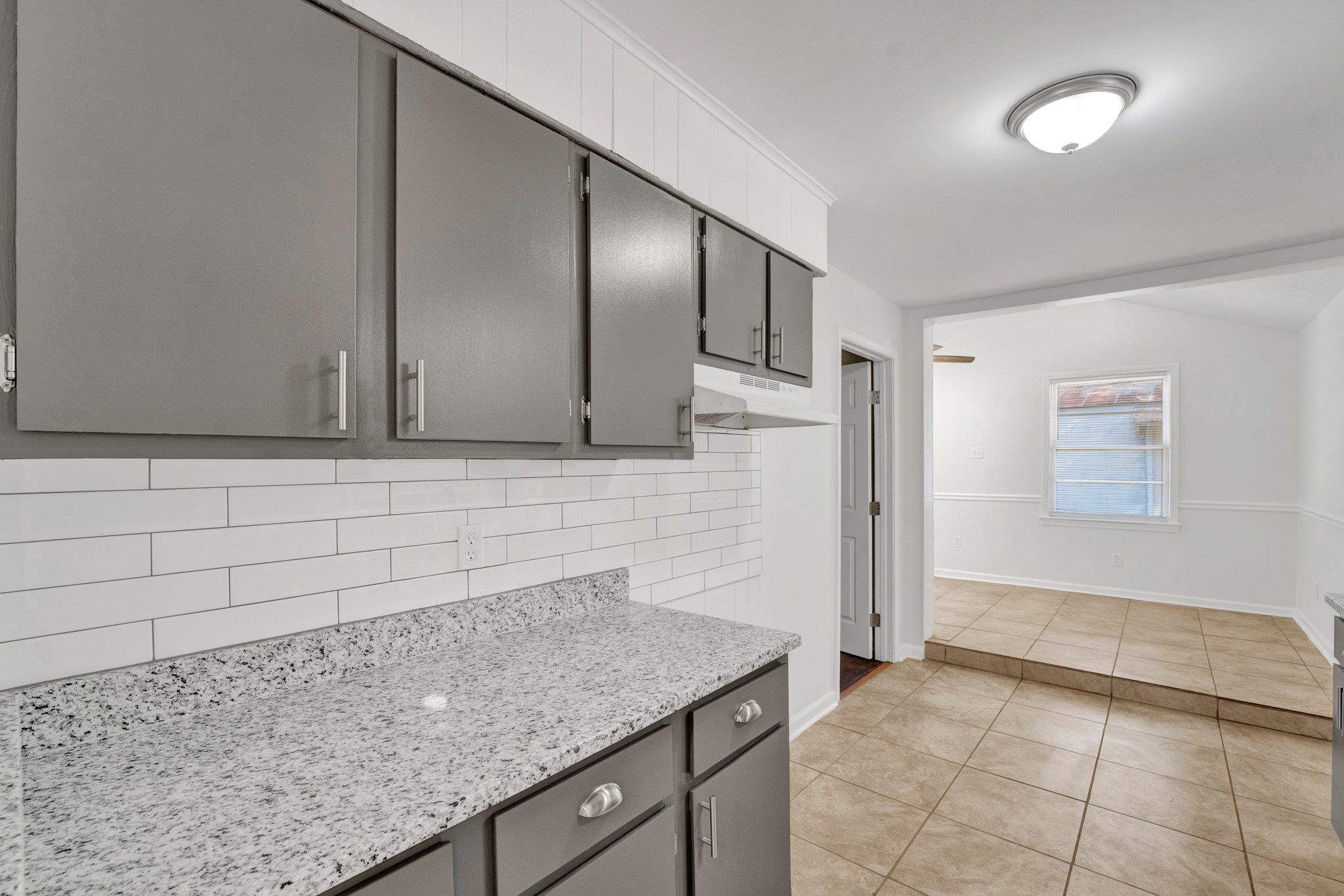 4382 Ruth Drive Memphis, TN 38109 - Photo 10 of 32 Kitchen featuring gray cabinets, light tile patterned flooring, light stone counters, and backsplash