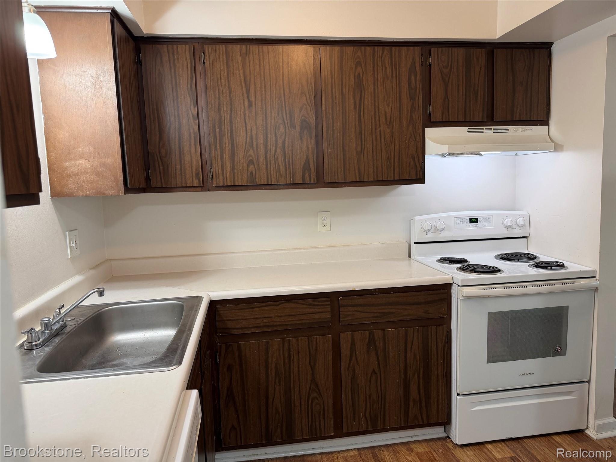 23600 Kelly Road, Unit #6 Eastpointe, MI 48021 - Photo 3 of 11 Kitchen featuring wood-grain cabinetry, a stainless steel sink with a chrome faucet, a white electric range, and a matching range hood