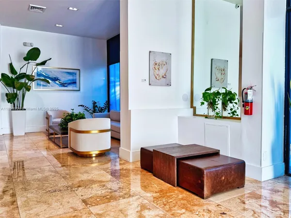 a living room with stainless steel appliances furniture a rug and a potted plant
