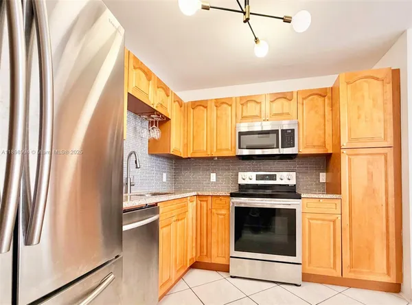 a kitchen with stainless steel appliances granite countertop a refrigerator a stove and a sink with wooden floor