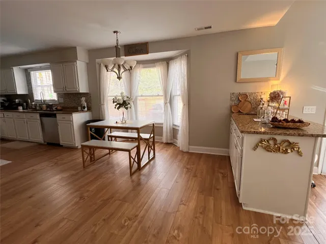 a kitchen with stainless steel appliances granite countertop wooden floors and white cabinets