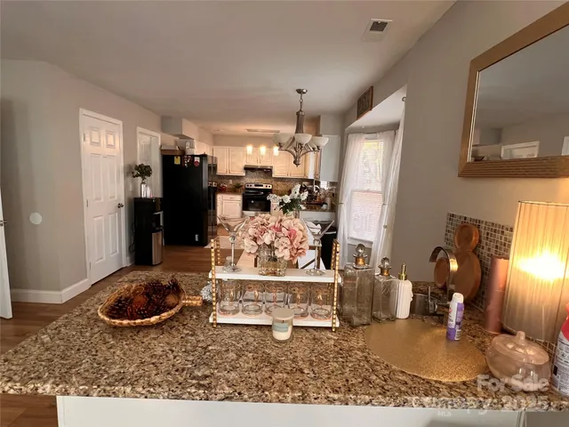 a dining room with stainless steel appliances kitchen island granite countertop furniture and a chandelier