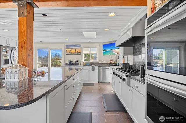 a large kitchen with stainless steel appliances granite countertop a sink and cabinets
