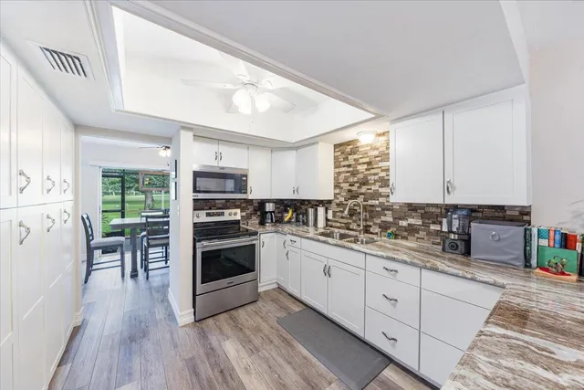 a kitchen with stainless steel appliances white cabinets a sink and a stove