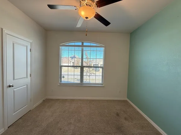 an empty room with a window and a chandelier fan