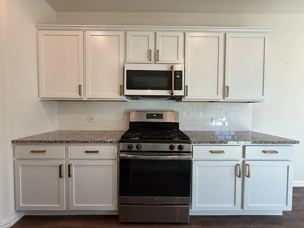 a kitchen with white cabinets and appliances