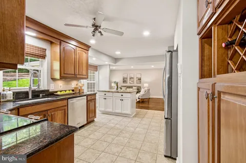 a kitchen with stainless steel appliances granite countertop a stove top oven a sink dishwasher a dining table and chairs with wooden floor