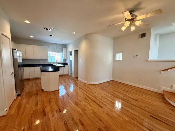 a kitchen with wooden floors white cabinets and stainless steel appliances