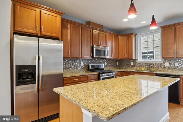 a kitchen with stainless steel appliances granite countertop a refrigerator a sink and a microwave