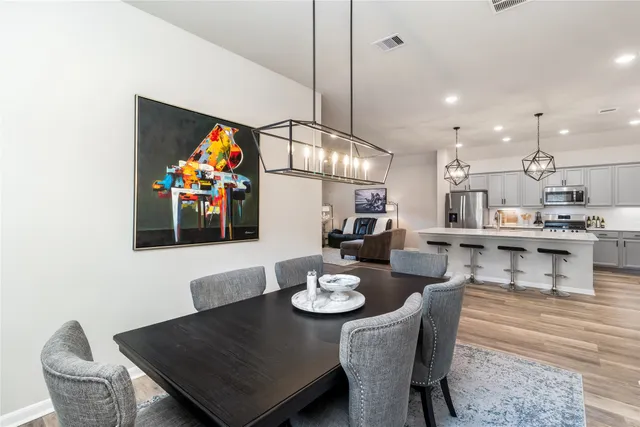 a view of a dining room and livingroom with furniture wooden floor a rug a painting and a chandelier
