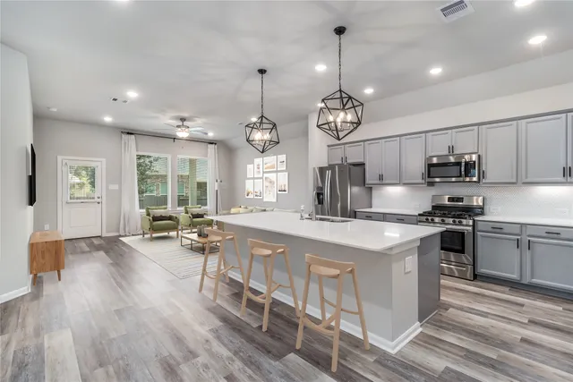 a large kitchen with stainless steel appliances granite countertop a stove oven a sink dishwasher and white cabinets with wooden floor