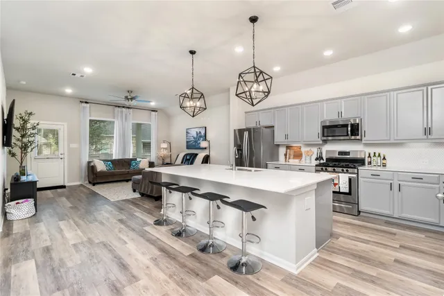 a kitchen with stainless steel appliances granite countertop a sink dishwasher a stove and a refrigerator with wooden floor