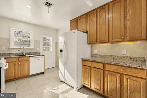 a kitchen with stainless steel appliances granite countertop a refrigerator and a stove top oven